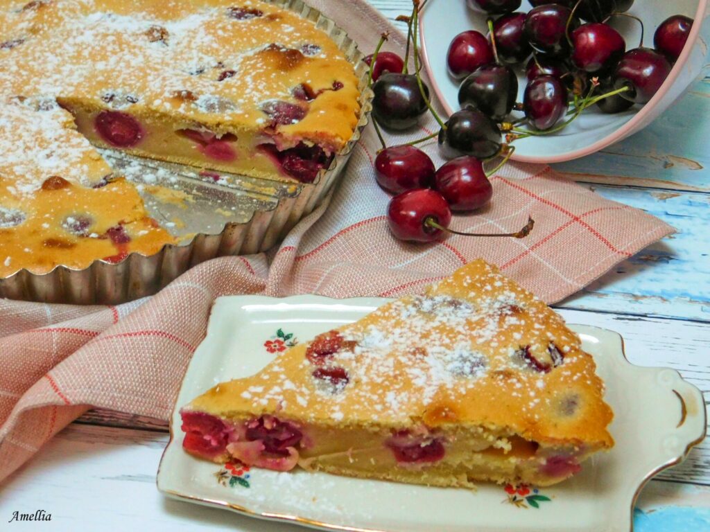 Detail na kousek koláče a vedle miska s třešněmi